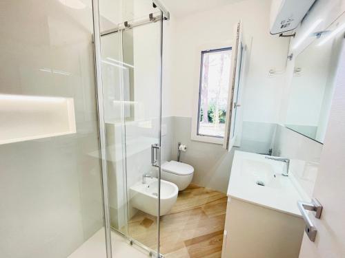a bathroom with a toilet and a glass shower at Villa Raffaella - Privat Garden in Bibione