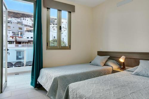 a hotel room with two beds and a window at Atico Albamar in Puerto de Mogán
