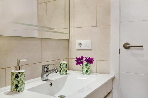 a bathroom with a sink with a mirror and purple flowers at Atico Albamar in Puerto de Mogán