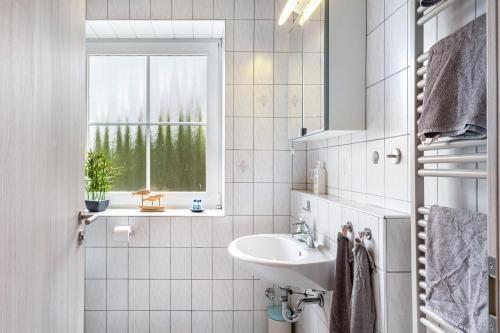 a white bathroom with a sink and a window at Kleiner Leuchtturm - Steuerbord in Fehmarn