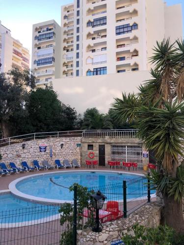 a swimming pool with chairs and buildings in the background at Squash Club Portimão in Portimão