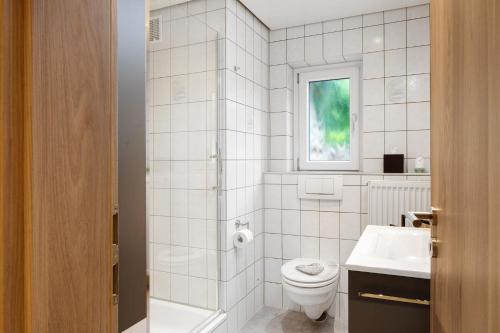 a white bathroom with a toilet and a sink at Gelis Ferienwohnung in Ihringen