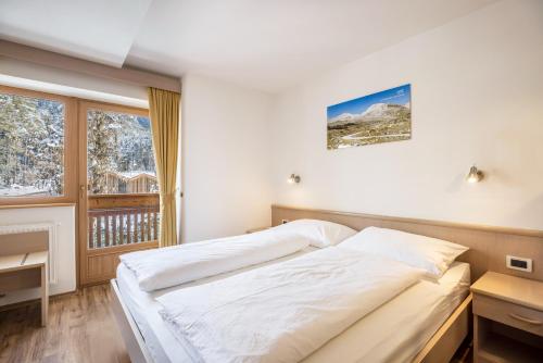 a bedroom with a bed and a balcony at Runcac Apt Salt in San Vigilio Di Marebbe