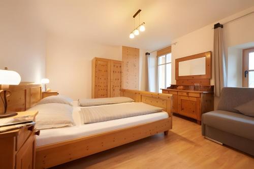 a bedroom with two beds and a tv and a chair at Rafaser - Apartment Rustika in Feldthurns