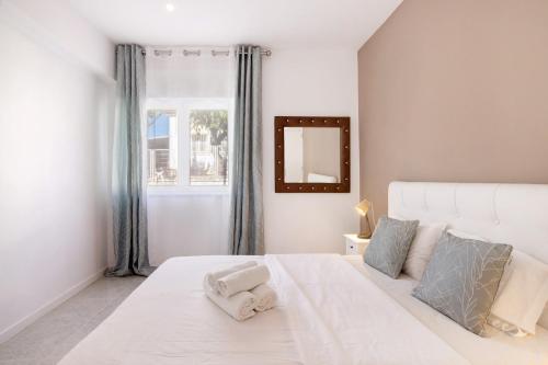 a white bedroom with a large white bed and a window at Apartamento Brisas Do Mar in Porches