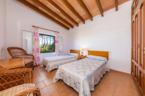 a bedroom with two beds and a table and a window at Finca Perello in Felanitx