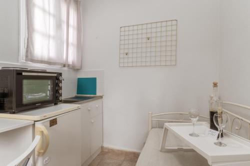 a small white kitchen with a table and a tv at Stenies Little Nook in Andros
