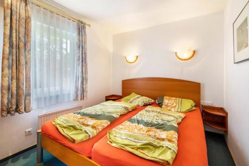 a bedroom with a bed with orange sheets and a window at Bungalow 179 in Zeulenroda