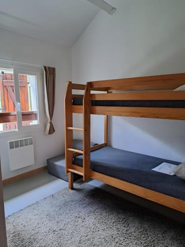 a bedroom with two bunk beds and a window at Duplex Près Du Lac De La Raviège in La Salvetat