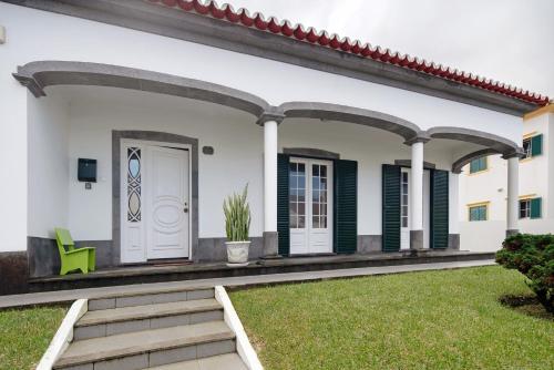 a white house with green shutters and a porch at Pascoal House in Ribeira Grande