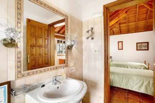 a bathroom with a sink and a mirror and a bed at Casita Ariadna in Tijarafe