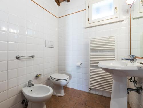 a white bathroom with a toilet and a sink at Podere Simonetta - A9 in Cecina