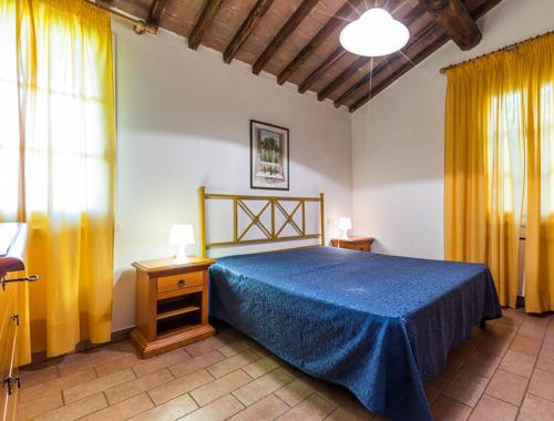 a bedroom with a blue bed and yellow curtains at Podere Simonetta - A9 in Cecina