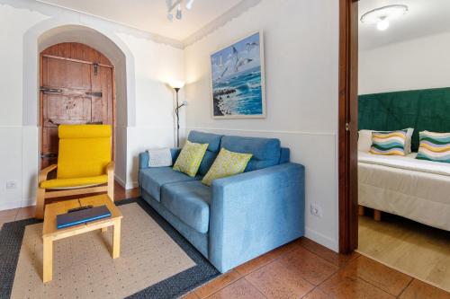 a living room with a blue couch and a bed at Casa do Largo - Acores in Ponta Delgada
