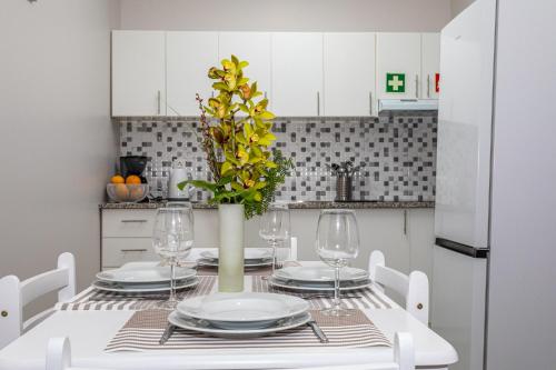 a white dining room table with a vase with yellow flowers at Oásis Fonte Grande in Santo António