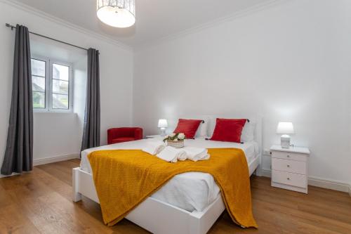 a white bedroom with a bed with a yellow blanket at Oásis Fonte Grande in Santo António