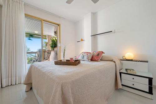 a white bedroom with a bed and a window at Apartamento Albatros in Cambrils