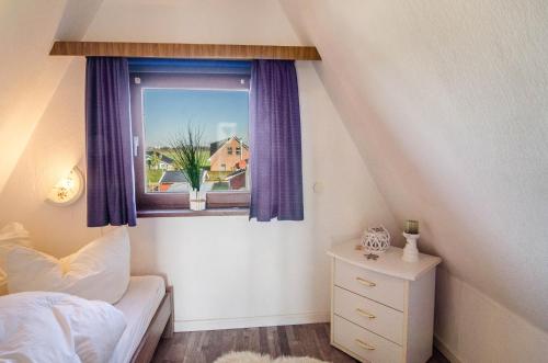 a bedroom with a bed and a window with purple curtains at Ferienhaus Kron in Südbrookmerland