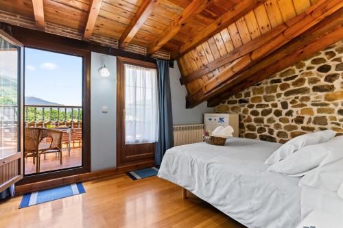 a bedroom with a bed and a stone wall at Casa El Campano in Ontaneda