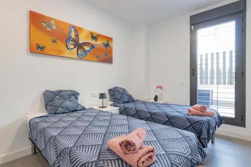 a bedroom with a bed and a butterfly painting on the wall at Adhara - 034 in Torre del Mar