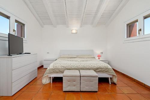 a white bedroom with a bed and a flat screen tv at Trilo Piazzetta Garden in San Teodoro