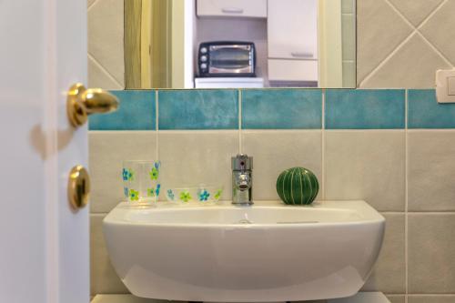 a bathroom with a white sink and a mirror at Gio's Apartment in Castelsardo