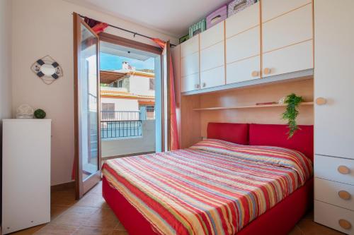 a bedroom with a red bed and a balcony at Gio's Apartment in Castelsardo