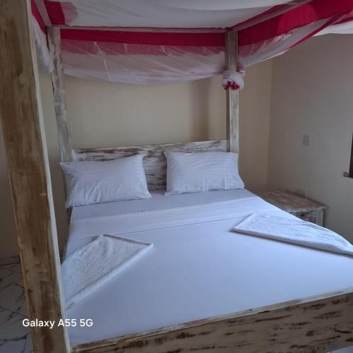 a bunk bed with white sheets and white pillows at Orange apartments 3 in Watamu