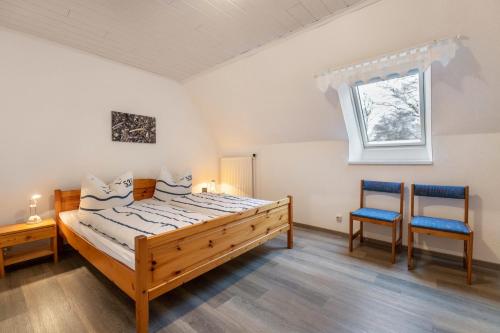 a bedroom with a wooden bed and two blue chairs at Ferienwohnungen Sterdebüll-Hof in Bordelum