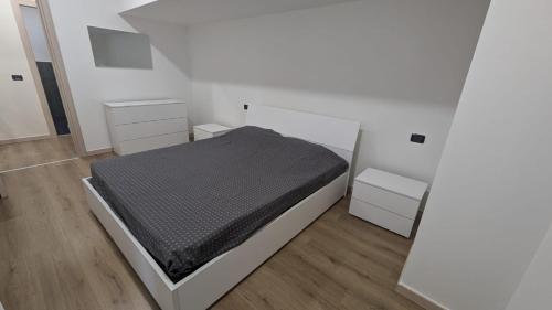 a white bedroom with a bed and two white cabinets at Casa Nicla in Colico