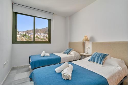two beds in a room with a window at Paraíso Azul in Nerja