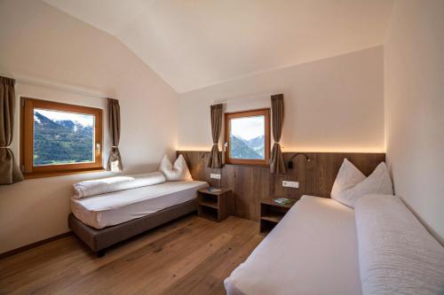 a hotel room with two beds and two windows at Flatschhof - Chalet Flatsch in Kastelbell-Tschars
