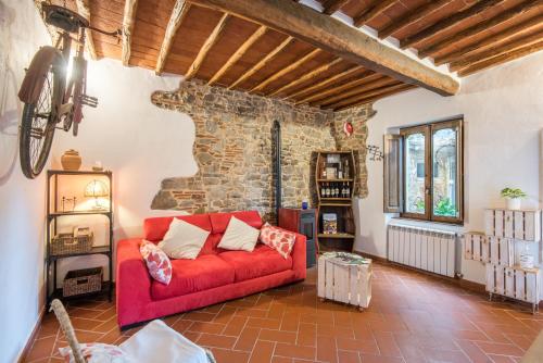 a living room with a red couch and a stone wall at L'arco della Fonte in Gaiole in Chianti