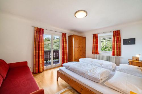 a bedroom with two beds and a couch and windows at Gasserhof Ferienwohnung Edelrot in Caines