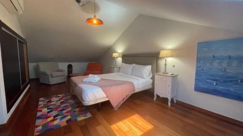 a bedroom with a bed and a chair and a painting at Villa Camacho xxvii in Arco da Calheta