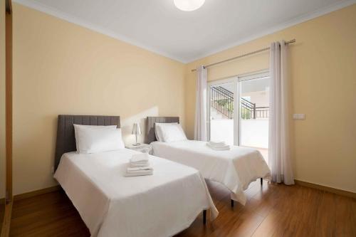 a bedroom with two beds with white sheets and a window at Cosy Two Bedroom Apartment in Cabaços