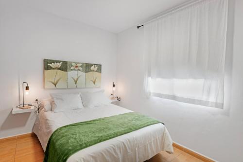 a white bedroom with a bed with a green blanket at Atico Olia in Los Llanos de Aridane