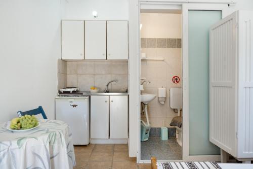 a kitchen with white cabinets and a table with a bowl of fruit at Ilias Studios Sevasti Kalymnos in Panormos Kalymnos