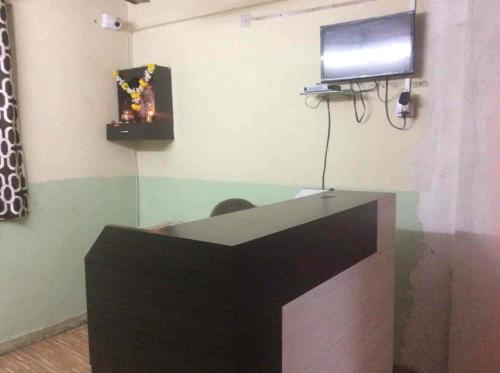 a desk with a flat screen tv on a wall at Laxmi Lodge in Pune