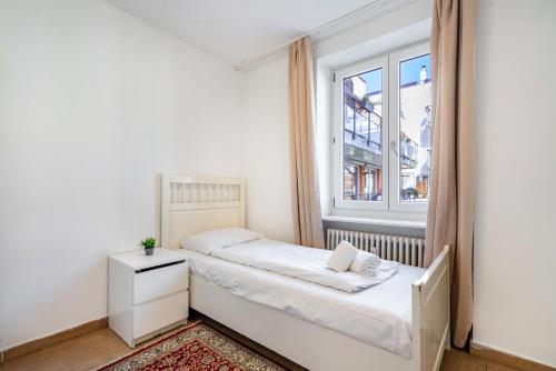 a small bedroom with a bed and a window at Aldars Urban Trio Suite No.5 in Munich
