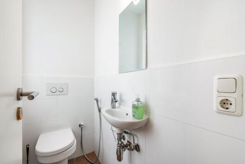 a white bathroom with a toilet and a sink at Aldars Urban Trio Suite No.5 in Munich