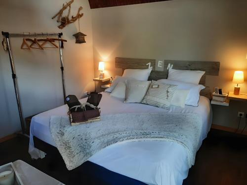 a bedroom with a large bed with two bags on it at Chambre d'hôtes Le Nid'zen in Le Nizan