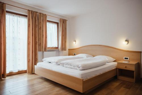 a bedroom with a large bed with white sheets at Ciasa Willy App Lavarella in La Villa