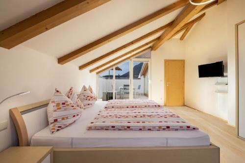 a bedroom with a large bed with red and white pillows at Stompferhof Mansarde in Caldaro