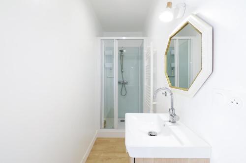 a white bathroom with a sink and a mirror at Chambres d'hôtes pleine nature in Plougonven