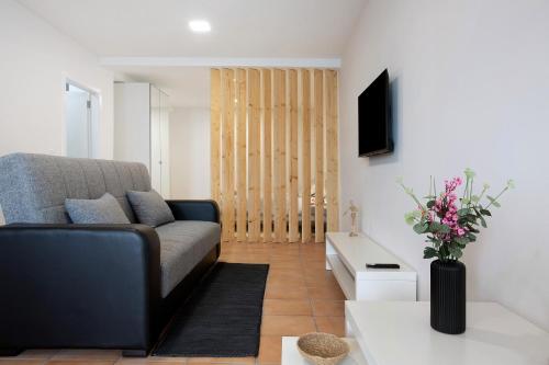 a living room with a couch and a vase of flowers at Babosas Charm in Funchal
