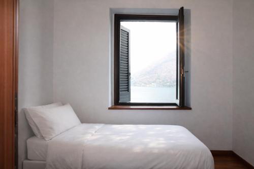 a bedroom with a white bed and a window at Emilia's Lakeview Terrace in Brienno