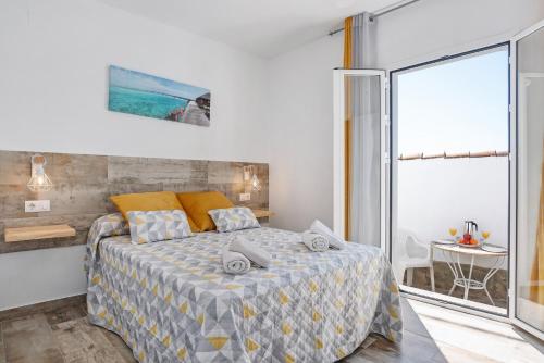 a bedroom with a bed and a window and a table at Casa Bombón in Vejer de la Frontera