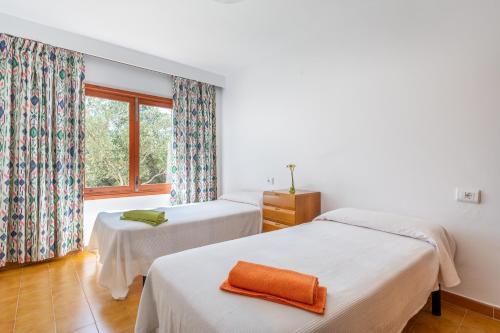 two beds in a room with a window at Es Jaç in Cala Llombards