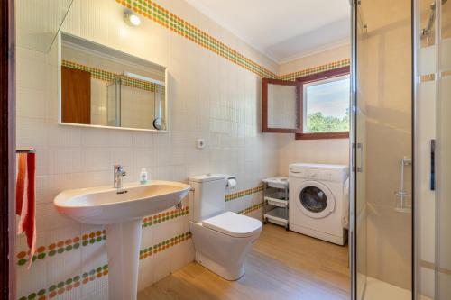 a bathroom with a toilet sink and a washing machine at Es Jaç in Cala Llombards